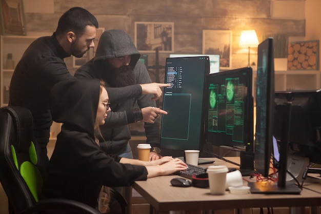 Hacker-Team, das auf Computerbildschirm und weibliche Cyber-Terroristin zeigt.