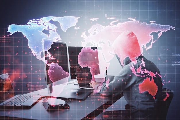 Hacker trabajando en múltiples computadoras con una superposición de mapa mundial digital