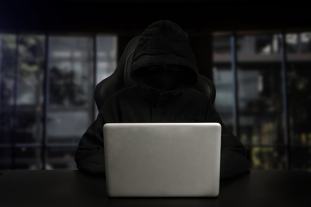 Hacker usando computador com interface digital enquanto está sentado na mesa do interior embaçado Hacking e conceito de ladrão