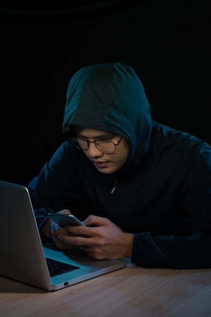 Hacker usando un teléfono inteligente. Ambiente nocturno muy oscuro