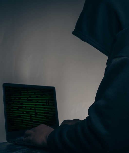 El hacker vestía una sudadera con capucha negra Robando enormes datos financieros en computadoras con código binario