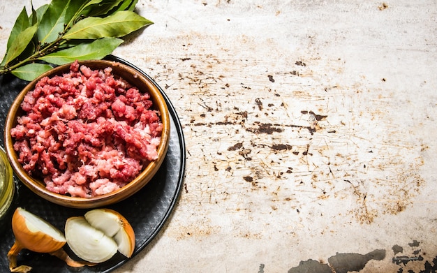 Hackfleisch in einer Holzschale mit Gewürzen und Öl