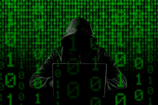 Hacking de ciberdelincuencia y concepto de delincuencia tecnológica Sin hacker facial con laptop con fondo de código binario