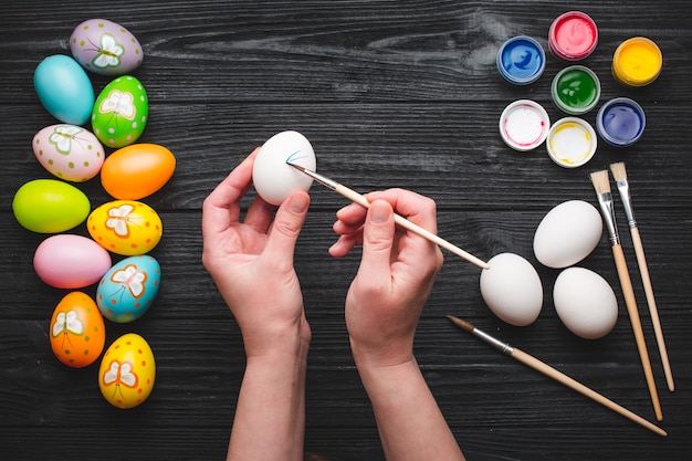 Hads pintando huevos para vacaciones de Semana Santa en mesa de madera