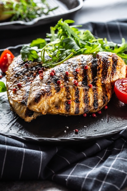 Hähnchenbrust gegrillt mit Gewürzen Pfeffersalz Tomaten und Rucola.