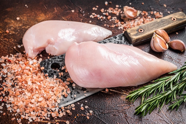 Hähnchenbrustfilet, frisches rohes Geflügelfleisch auf Metzgerbeil. Dunkler hölzerner Hintergrund. Ansicht von oben.