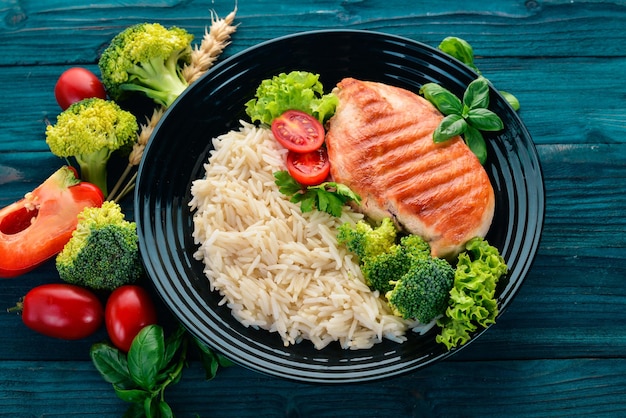 Hähnchenbrustgrill mit Reis und Gemüse Gesundes Essen auf einem blauen Holztisch Draufsicht Freier Platz für Text