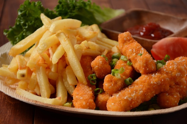 Hähnchenbrustnuggets mit beliebter Soße und Pommes und Gemüse zur Auswahl auf Holzhintergrund