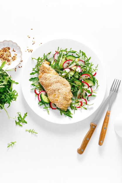 Hähnchenfilet gebacken in Semmelbröseln und frischem Gemüsesalat aus Rettich und Gurke Draufsicht