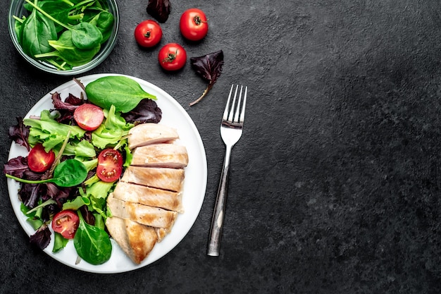 Hähnchenfilet mit Salat und Spinat Gesundes Essen auf Steintisch