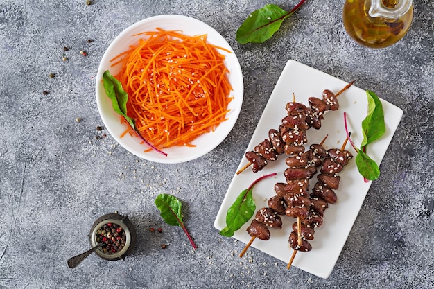 Hähnchenherzen in scharfer Soße und Möhrensalat. Gesundes Essen. Draufsicht