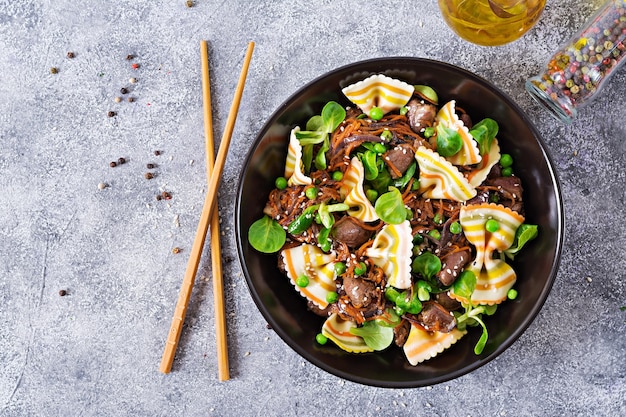 Hähnchenherzen mit Karotten in süß-saurer Soße mit Farfalle-Nudeln. Flach legen.