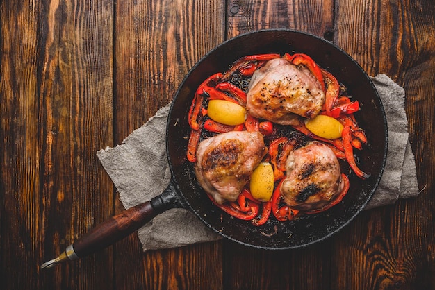 Hähnchenschenkel gebacken mit roter Paprika, Rosmarin und Zitrone in Gusseisenpfanne Ansicht von oben