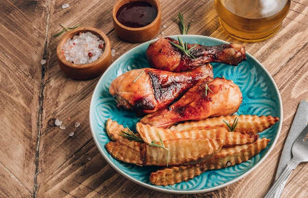 Hähnchenschenkel mit Pommes Frites auf einem blauen Teller