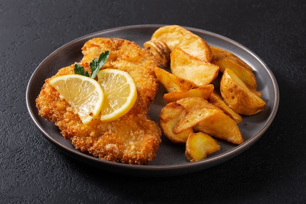 Hähnchenschnitzel mit Idaho-Kartoffeln auf einem dunklen Teller