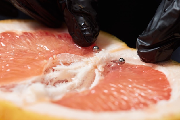 Hälfte der Grapefruit mit vertikalem Barbell-Piercing auf einem Hintergrund