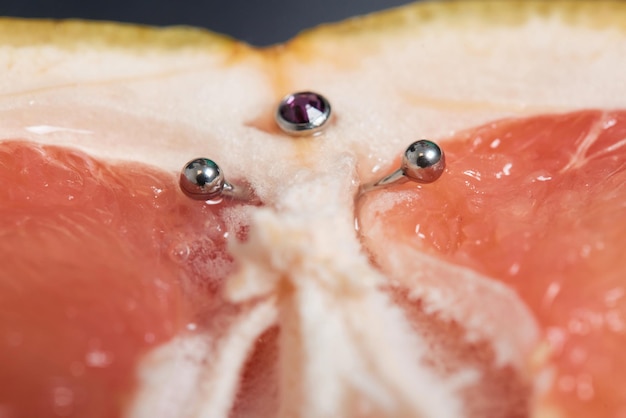 Hälfte der Grapefruit mit vertikalem Barbell-Piercing auf einem Hintergrund