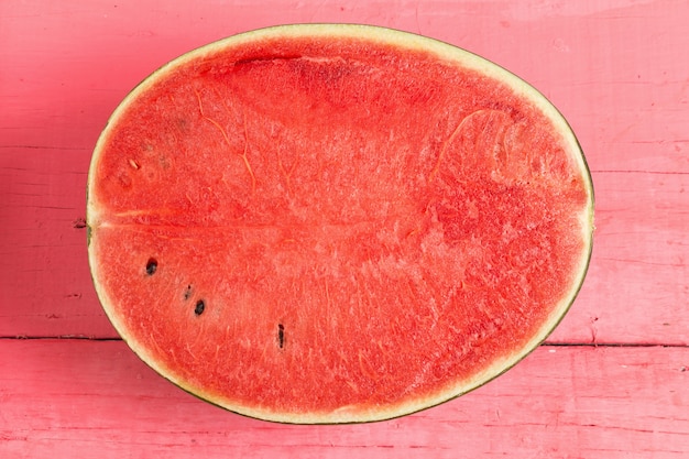 Hälfte der reifen Wassermelone auf hölzernem Rosa