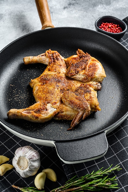 Hälften des gegrillten saftigen Huhns mit goldbrauner Kruste in einer Pfanne. Ansicht von oben