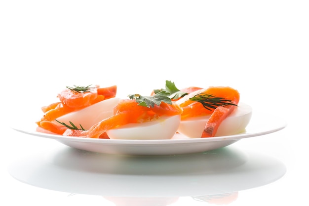 Hälften gekochter Eier mit gesalzenen Lachsstücken isoliert auf weißem Hintergrund