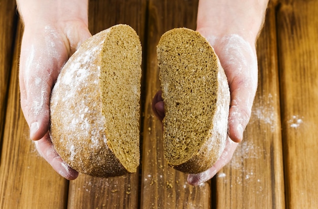 Hälften von frischem Brot in den Händen des Bäckers.