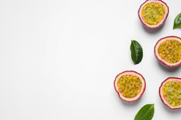 Hälften von Passionsfrüchten Maracuyas und grünen Blättern auf weißem Hintergrund flach liegend Platz für Text