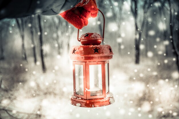 Hält eine rote Kerzenlaterne im Winterwald