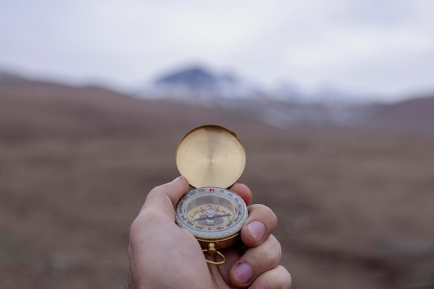 Hält einen Kompass vor dem Hintergrund eines Berges
