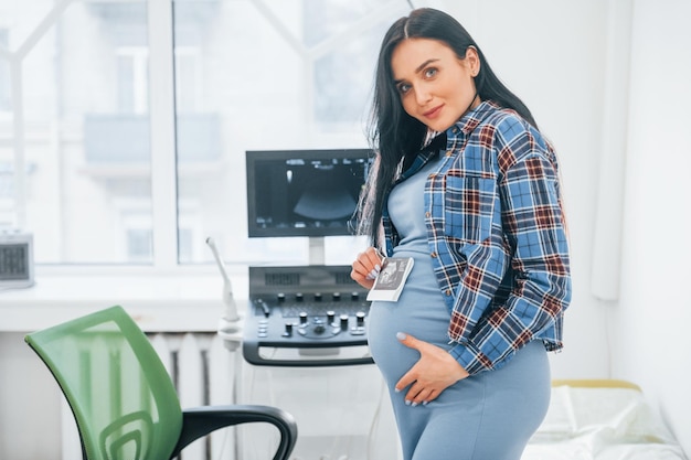 Hält Ergebnisse der Ultraschalluntersuchung Schwangere Frau ist in der Klinik im Kabinett und hat einen Gesundheitscheck