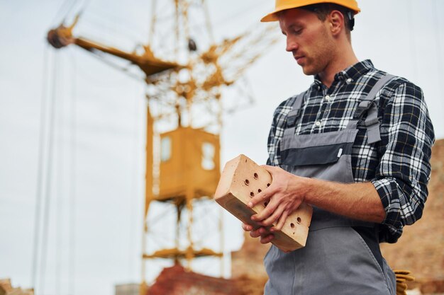 Hält Ziegel Bauarbeiter in Uniform und Sicherheitsausrüstung haben Arbeit am Bau