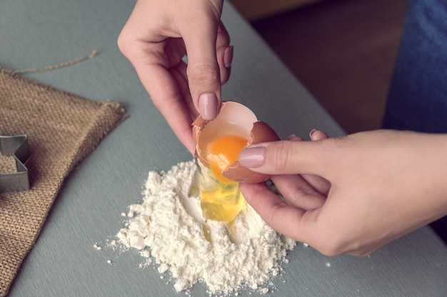 Hände brechen ein Hühnerei in Mehl