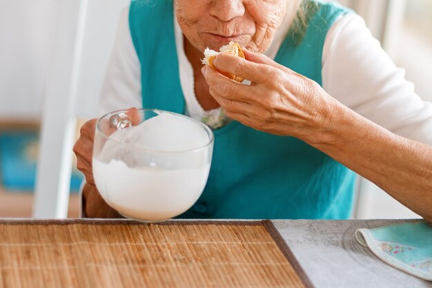 Hände der älteren Frau, die große Tasse Joghurt halten