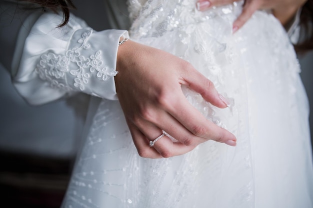 Hände der Braut an einem Hochzeitskleid