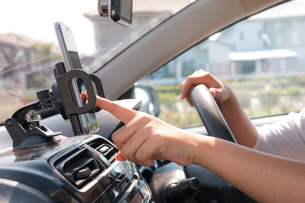 Hände der Frau, die intelligentes Mobiltelefon im Auto für bewegliche Technologie verwendet