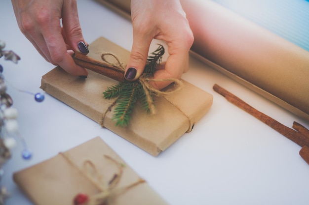 Hände der Frau, die Weihnachtsgeschenkkasten verziert Hände der Frau