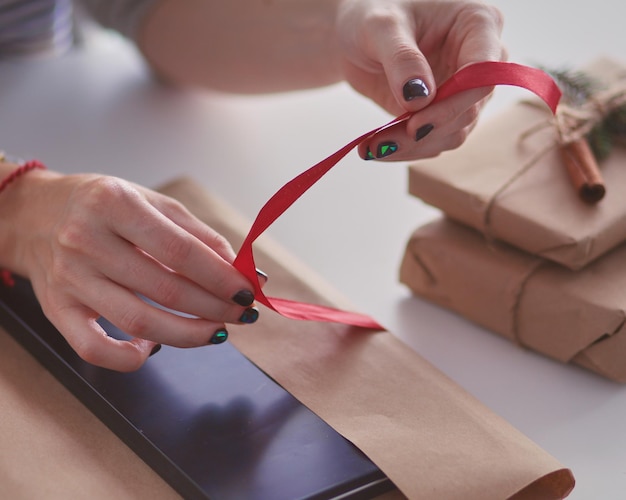 Hände der Frau, die Weihnachtsgeschenkkasten verziert Hände der Frau