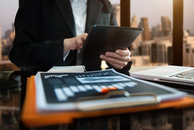 Hände der Frau mit Handy im modernen Büro mit Laptop und digitalem Tablet im Home Office