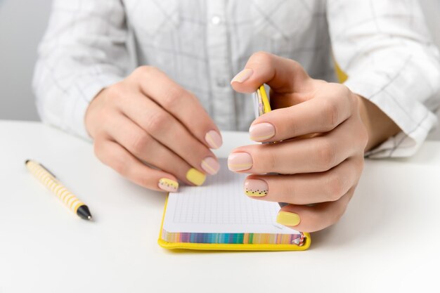 Hände der gepflegten Frau, die einen Stift und einen Notizblock halten. Flache Lage, Draufsicht arbeiten zu Hause Büro Bildungskonzept.