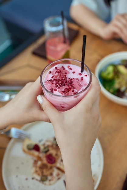 Hände der jungen frau, die frisch gepresste erdbeerlimonade aus zitrusfrüchten halten weibchen mit einmachglas voller kalter cocktail-zitronen-orangen-limetten-minzblätter