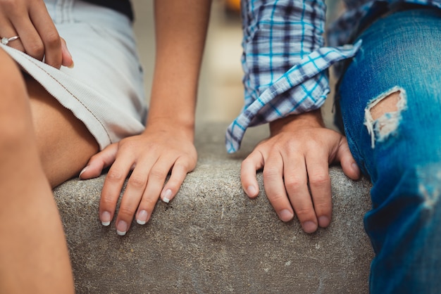 Hände der jungen Paare in der Liebe schließen nebeneinander am ersten Datum