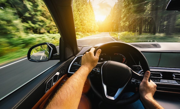 Hände des Autofahrers am Lenkrad, Autofahren an Sommertagen auf einer Landstraße, Spaß am Fahren auf der leeren Autobahn auf Tourfahrt - POV, First-Person-View-Aufnahme