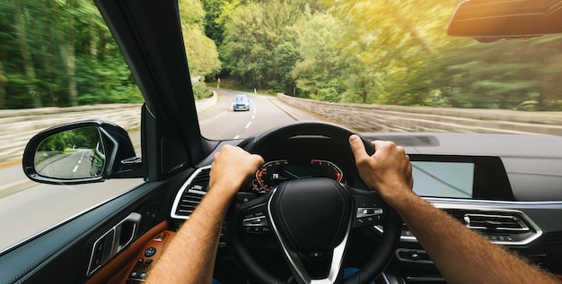 Foto hände des autofahrers am lenkrad, schnell fahrendes auto am frühlingstag auf einer landstraße, die spaß daran haben, die leere autobahn auf tourfahrt zu fahren pov first person view shot