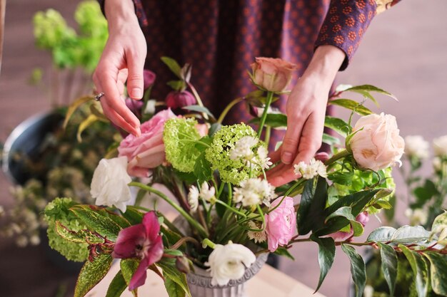 Hände des floristen sammeln hochzeitsblumenstrauß. florist bei der arbeit