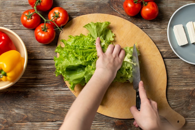 Hände des Mädchenausschnittkopfsalates auf einer Tabelle