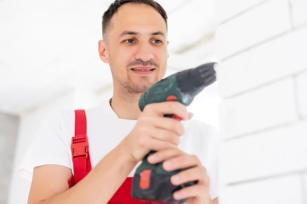 Hände des Meisters in Handschuhen kleben vor dem Anbringen an einer Wand einen Zierstein auf