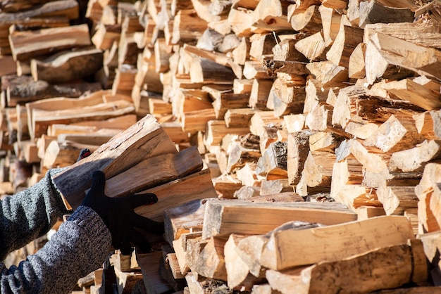 Hände des Menschen stapeln Brennholz im Stapel und bereiten sich auf die kalte Jahreszeit im Dorf vor, um das Haus zu heizen