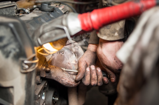 Hände des Schlossermechanikers arbeitend an Motor unter Verwendung des Werkzeugs