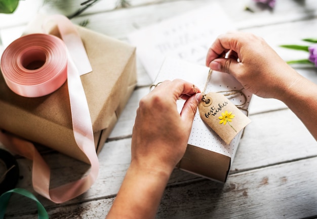 Hände, die anwesenden Kasten mit Blumen-Dekorations-Handwerk einwickeln