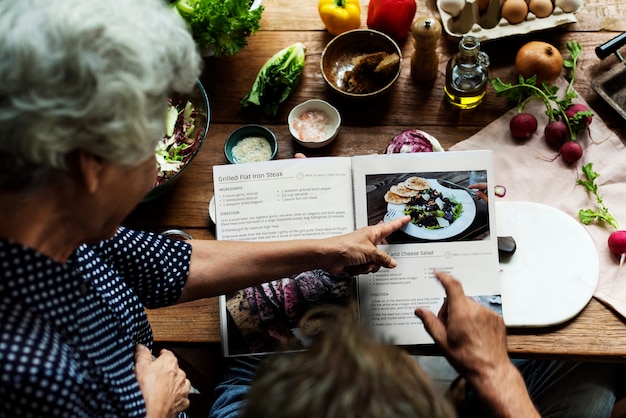 Hände, die auf kochendes Buchrezept zeigen