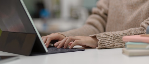 Hände, die auf Tabletttastatur am Schreibtisch tippen